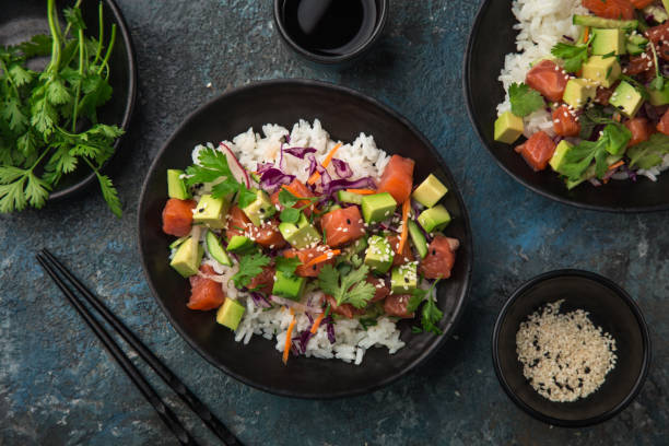 avocado and salmon poke bowl, dark background, top view